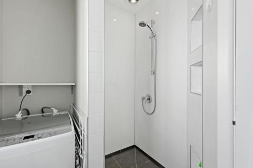 a white bathroom with a shower and a sink at Coastal City Retreat - New Brighton Accommodation in Christchurch