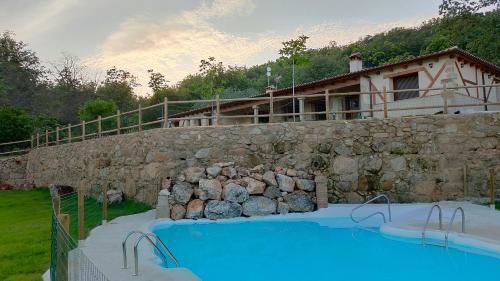 une grande piscine à côté d'un mur en pierre dans l'établissement Hotel Rural San Giles, à Jarandilla de la Vera
