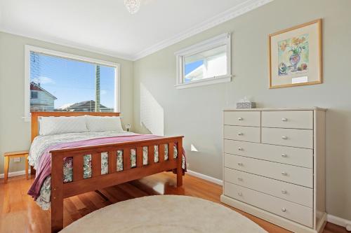 a bedroom with a bed and a dresser and a window at Coastal City Retreat - New Brighton Accommodation in Christchurch