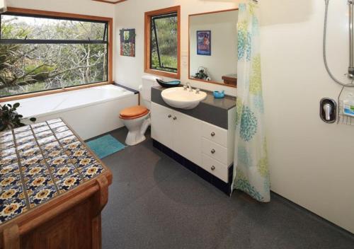 a bathroom with a tub and a sink and a toilet at Waiheke Escape in Palm Beach