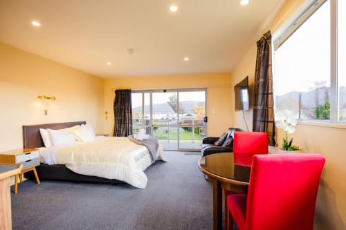 a bedroom with a bed and a desk and a window at Alpine View Motel in Te Anau