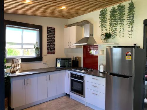 a kitchen with white cabinets and a stainless steel refrigerator at Moore St Cottage in Ohakune