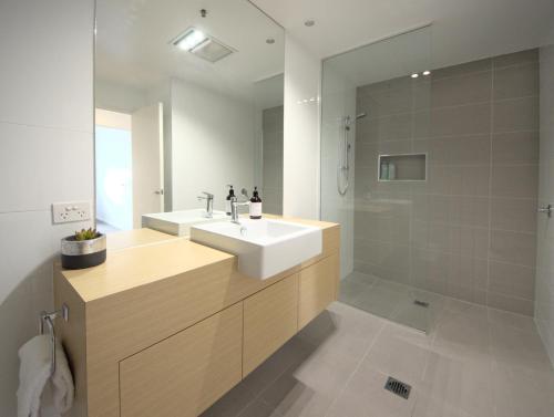 Kangaroo Bay Apartments في هوبارت: حمام مع حوض أبيض ودش