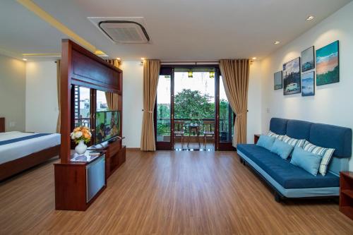 uma sala de estar com um sofá azul e uma televisão em Sol Villa em Hoi An