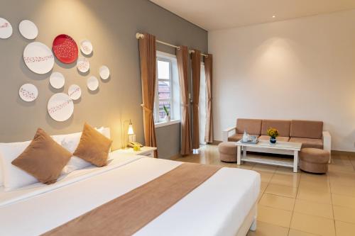 a bedroom with a large white bed and a couch at Alba Hotel in Hue