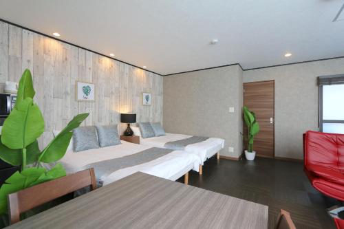 a hotel room with three beds and a table at Liz5 Guest House Liz Nakazakicho in Osaka