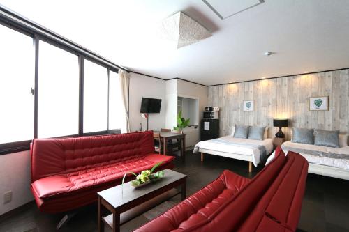 a living room with a red couch and a bed at Liz5 Guest House Liz Nakazakicho in Osaka