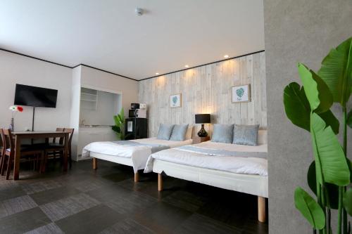 two beds in a room with a table and chairs at Liz5 Guest House Liz Nakazakicho in Osaka