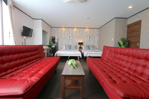a living room with red leather couches and a bedroom at Liz5 Guest House Liz Nakazakicho in Osaka