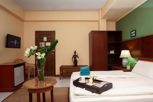 a hotel room with a bed and a table with flowers at People Place Classic Hotel SHA Extra Plus in Chiang Mai