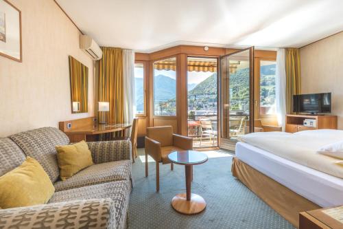 ルガノにあるHotel Delfino Luganoのベッドとソファ付きのホテルルーム