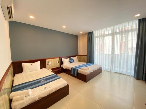 a bedroom with two beds and a large window at Hung Phuoc Hotel in Bến Cát