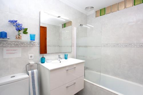 Un baño blanco con lavabo y espejo. en Albers Apartment, en Puerto de Alcudia
