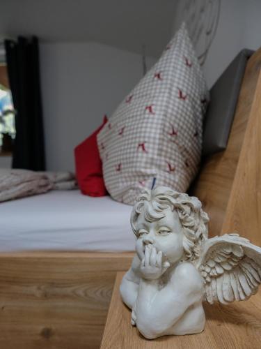 a statue of an angel sitting on a table next to a bed at Ferienwohnungen Hechenblaikner in Maurach