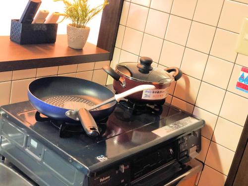 a pan on a stove with a pot on it at COCOSTAY Matoba ココステイ広島駅前 in Hiroshima