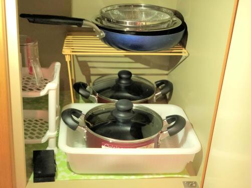 a refrigerator with two pots and pans on a shelf at COCOSTAY Matoba ココステイ広島駅前 in Hiroshima