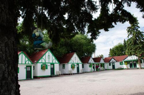 a row of white and green houses with a tree at Chalet Motel in Custer