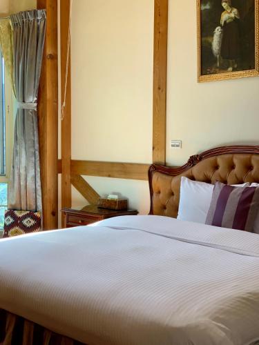a bedroom with a white bed with a wooden headboard at The Cotswolds Villa in Renai