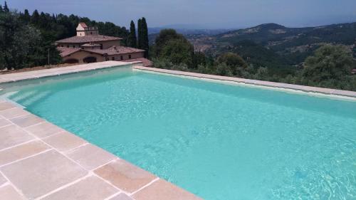 ein großer Pool mit einem Haus im Hintergrund in der Unterkunft Tenuta La Novella in Poggio Alla Croce