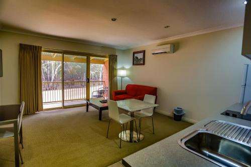 a living room with a table and a red couch at Murray Waters Motor Inn & Apartments in Koondrook