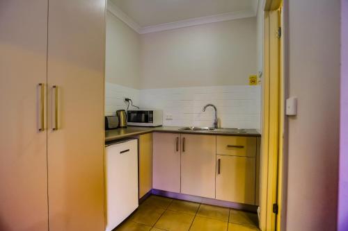 a small kitchen with a sink and a microwave at Murray Waters Motor Inn & Apartments in Koondrook
