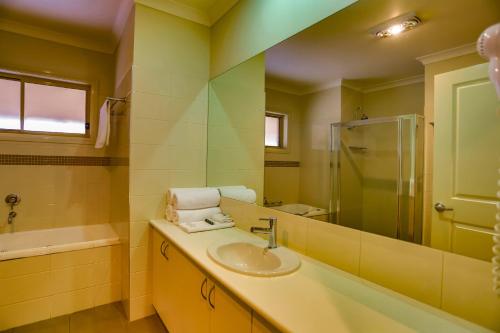 uma casa de banho com um lavatório, um chuveiro e um espelho. em Murray Waters Motor Inn & Apartments em Koondrook