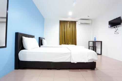 a bedroom with a large bed with white sheets at Lux Hotel in Teluk Intan