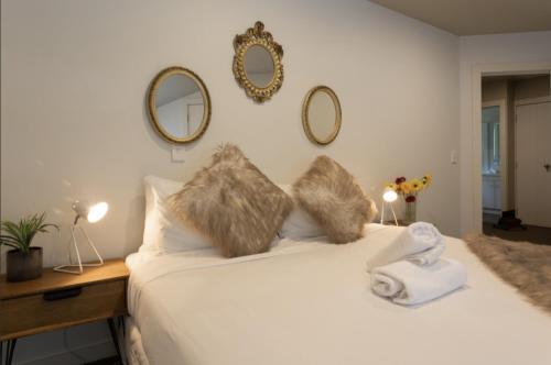 una camera da letto con un letto bianco con cuscini in pelliccia e specchi di Lake Escape a Queenstown