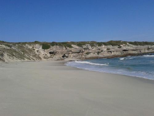 a sandy beach with the ocean and rocks at Haus Giotto in Gansbaai