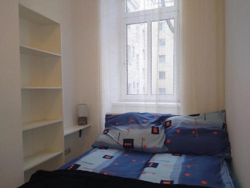 a bedroom with a bed with blue sheets and a window at Spacious Central Apartment in Vienna