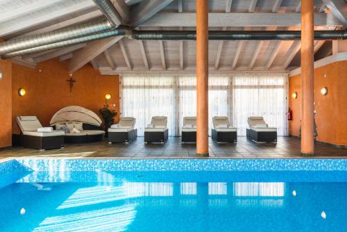 a swimming pool in a building with chairs at Hotel Moserhof in Terento