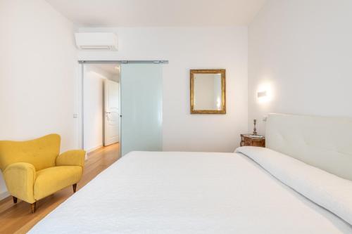 a bedroom with a white bed and a yellow chair at A Luxury apartment at Cagliari Poetto Beachfront in Cagliari