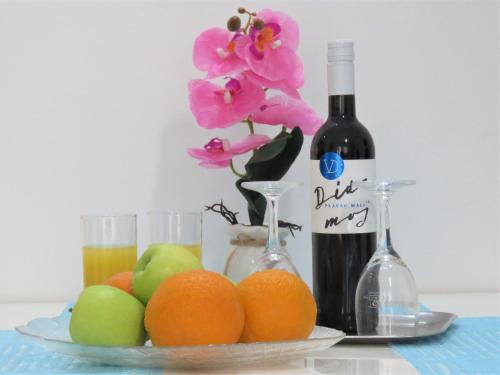 un piatto di frutta con una bottiglia di vino e fiori di Apartmani Villa Delija Klek a Klek