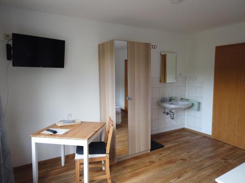 Zimmer mit einem Tisch und einem Bad mit einem Waschbecken in der Unterkunft Hotel Waldterrasse in Rengsdorf