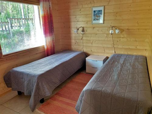 1 dormitorio con 2 camas y ventana en Lappalaisen lomamökit Mäntypirtti en Puumala