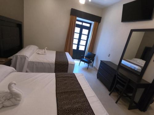 a hotel room with two beds and a mirror at Hotel San Diego in Guanajuato