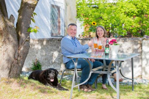 a man and woman sitting at a table with a dog at Ferienwohnungen Windischeschenbach by HausGruenerBaum in Windischeschenbach