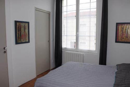 Schlafzimmer mit einem Bett und einem Fenster in der Unterkunft Résidence Pasteur - flyer in Rochefort