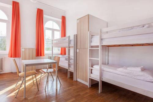 a bedroom with bunk beds and a table and a desk at Hostel DIC in Ljubljana