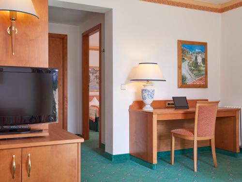 a hotel room with a television and a desk with a lamp at Travel Charme Nordperd & Villen in Göhren
