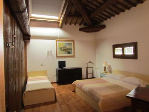 a bedroom with two beds and a desk and a television at Ristorante Alloggio Ostello Amolara in Adria
