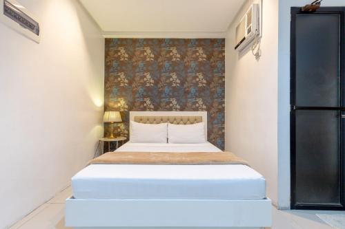 una camera con un letto bianco e un muro di Baymont Suites & Residences a Manila