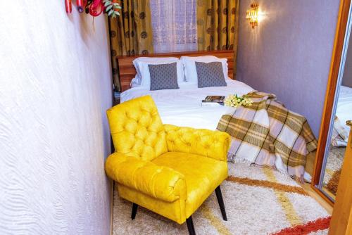 a bedroom with a bed and a yellow chair at TOPILCHE APARTMENT in Ternopil