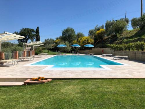 a swimming pool with chairs and umbrellas in a yard at Agriturismo Casale Giulia in Volterra