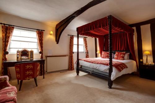 a bedroom with a canopy bed and a desk at The Saracens Head Hotel in Southwell