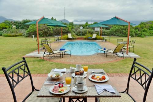 a table with plates of food on it next to a pool at Town Lodge George in George