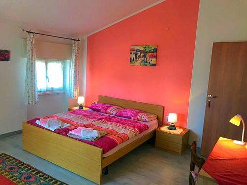 una camera con un letto con una parete rossa di Ferienwohnungen Sponchie a Lazise