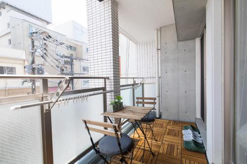 a balcony with a wooden table and chairs at CANAL RISE-良いロケーション-固定Wifi-ワーケーションにも最適! in Fukuoka