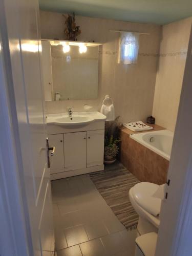 a bathroom with a sink and a tub and a toilet at Harbour View House in Mythimna