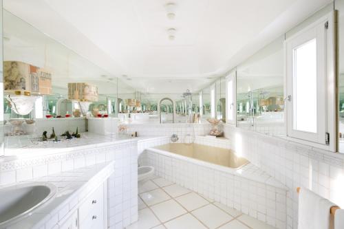 La salle de bains blanche est pourvue de 2 lavabos et d'une baignoire. dans l'établissement Luxury Relais Villa Magdalena, à Ischia